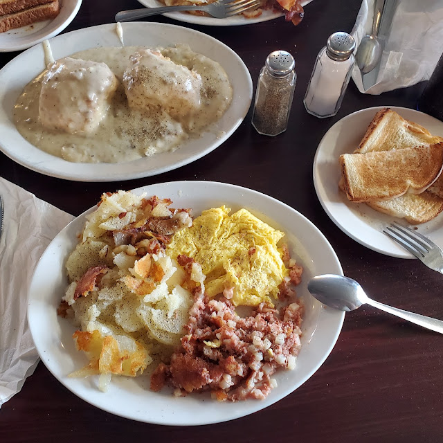Scrambled Eggs Hash Home Fries Sharing Some Biscuitsw Gravy with Hot Sause on the Side